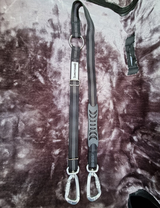 Two black dog leashes with metal clips on a textured surface
