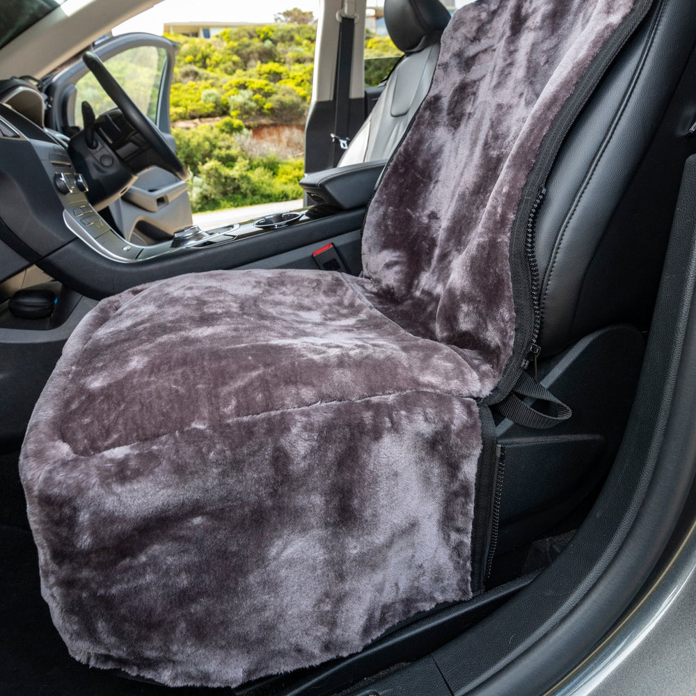 Gray plush car seat cover on a vehicle seat with a blurred outdoor background