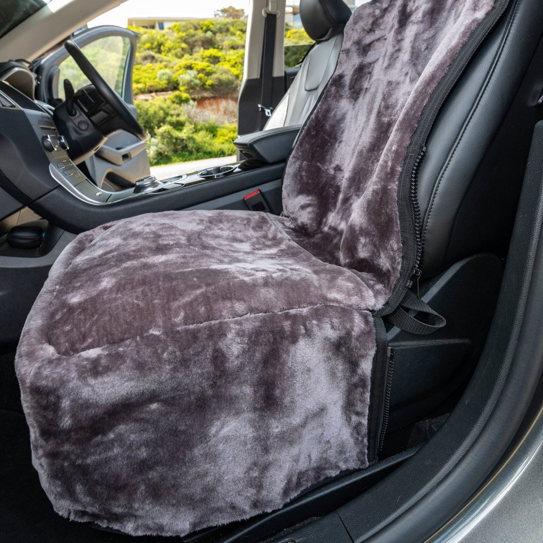 Gray plush car seat cover on a vehicle seat with a blurred outdoor background